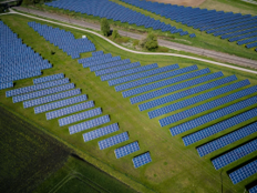 Luftaufnahme einer Photovoltaik-Freiflächenanlage mit mehreren Reihen von Solarmodulen.