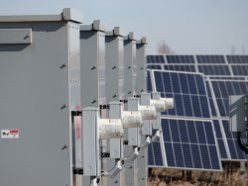 Reihe elektrischer Schaltschränke neben den Solarmodulen einer Photovoltaikanlage.